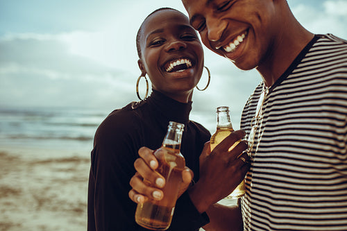Couple on vacation having beers at the beach
