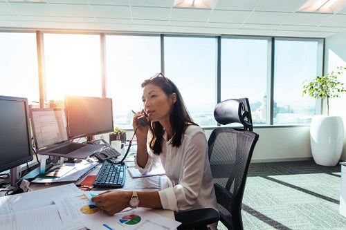 Businesswoman speaking over phone in office.