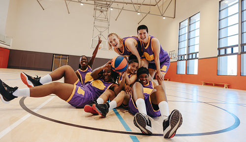 Happy basketball team celebrating victory on indoor court