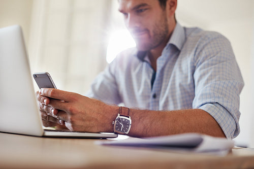 Yung businessman using mobile phone at home