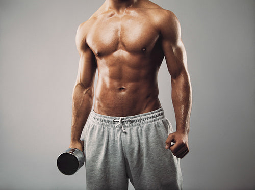 Masculine man in holding dumbbell on grey background