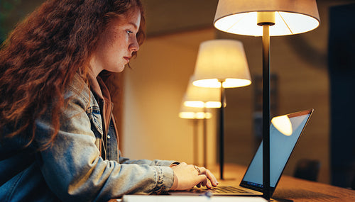 Girl studying on laptop late night in college library