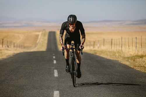 Sportsman riding bicycle on the long road