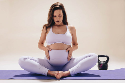 Yoga for a healthy baby bump: Peaceful mom meditating in studio during the third trimester