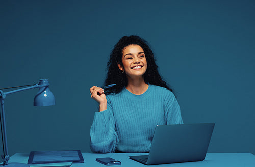 Cheerful female graduate in a blue monochromatic setting