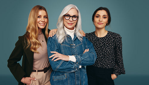 Group of three women smiling at the camera in a studio