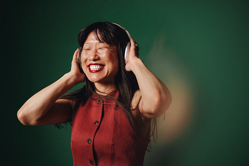 Leisure time finds woman smiling in headphones against a green background