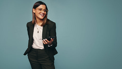 Smiling young woman holding a smartphone in a studio