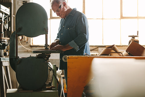Senior worker working on band saw machine
