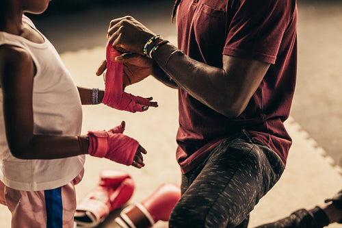 Boxing kid putting on bandages before wearing boxing gloves
