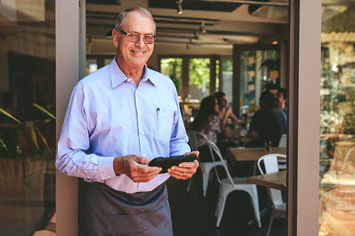 Successful male cafe owner standing at the entrance door