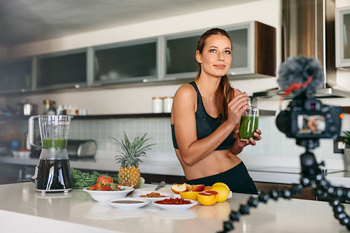 Young woman recording content for her video blog in kitchen.
