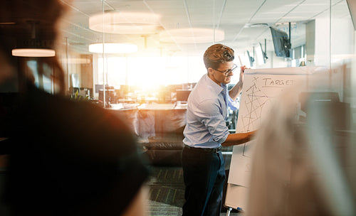 Businessman giving presentation to coworker in modern office