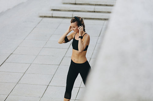 Aerial view of a fitness woman walking outdoors listening to music