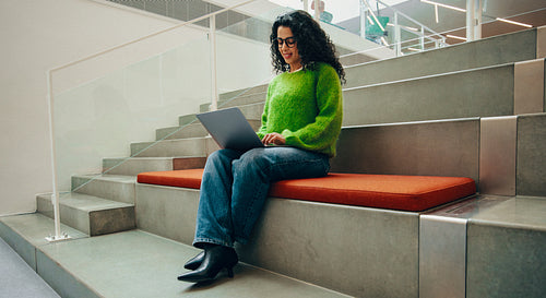 Postgraduate student using laptop in modern library seating area