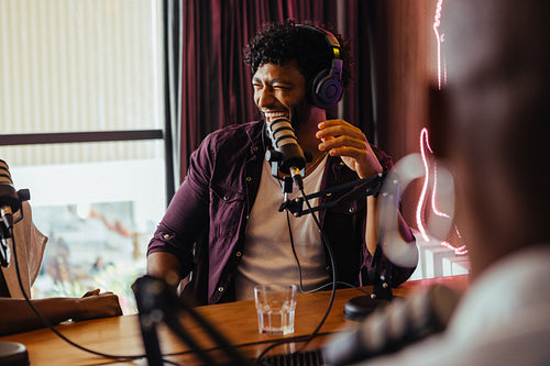 Happy radio host engaged in lively discussion with guest during podcast recording