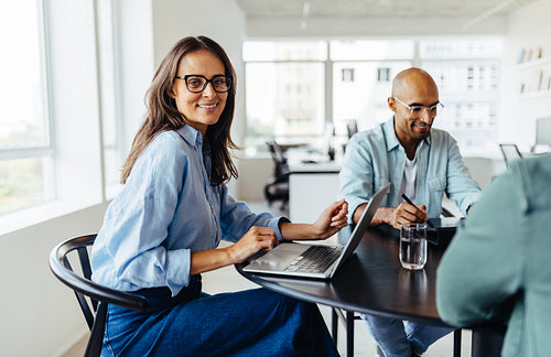 Mature designer sitting at a table with her colleagues
