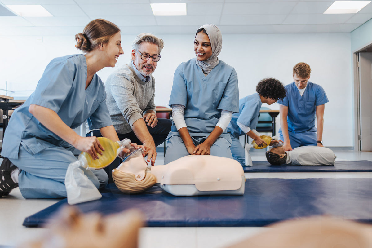 Mature doctor teaching students how to do CPR in a medical simulation ...