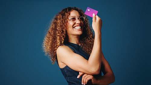 Strong woman with bank card representing financial independence in studio portrait