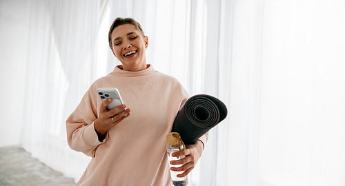 At home, the woman checks her phone before a yoga workout