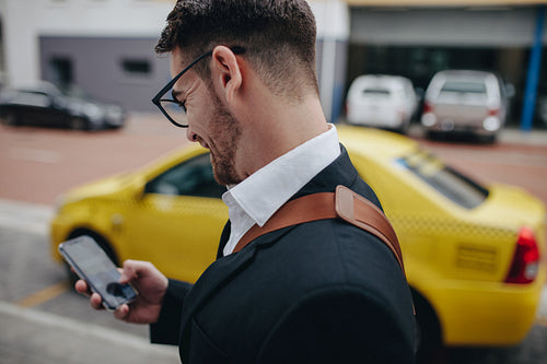 Businessman using mobile phone while walking on street