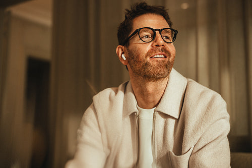 Smiling businessman with earbuds enjoys a moment in a cozy office setting