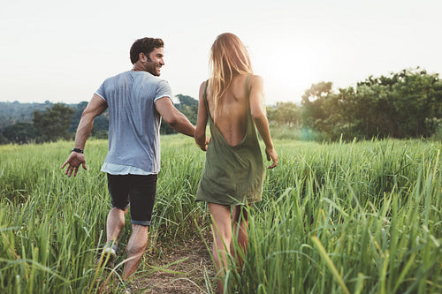 Young couple walking through grassy field