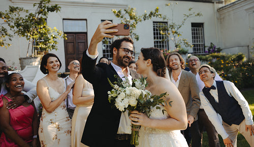 Bride and groom taking a selfie with joyful friends at an outdoor micro wedding