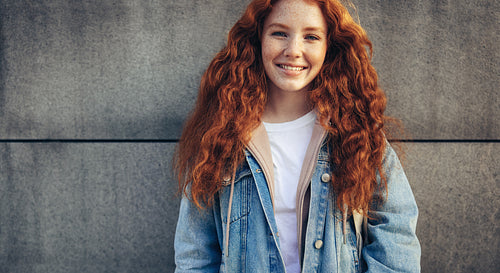 Cheerful student standing against wall background