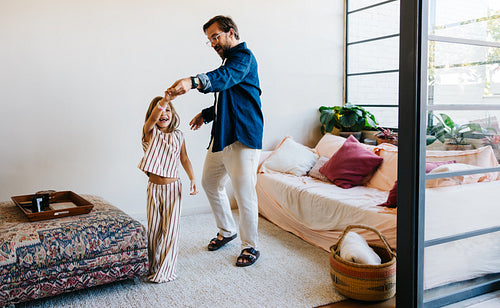 Father dances with daughter at home playtime