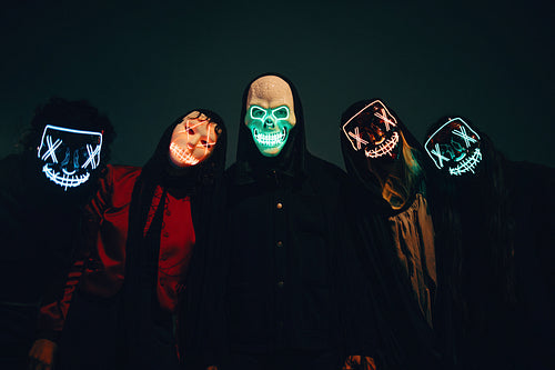 Group with neon masks under dark atmospheric lighting