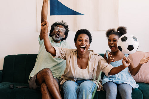 Family celebrating game day at home: Cheerful supporters watching football