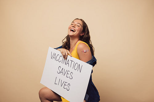 Woman laughing holding a banner of "Vaccination saves lives"