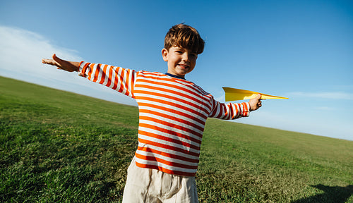 Boy with paper plane enjoys freedom and fun in sunny field