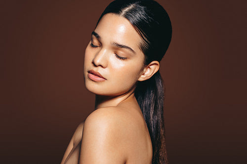 Consistent skincare gives radiant and flawless skin. Beautiful woman standing in a studio with her eyes closed