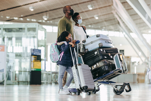 African family with face masks waiting at airport terminal