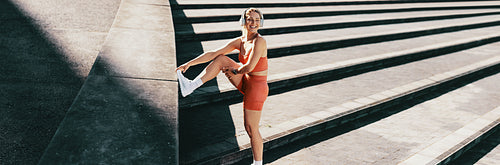 Active and energetic female athlete smiling while stretching, exercising, listening to music and enjoying a healthy lifestyle