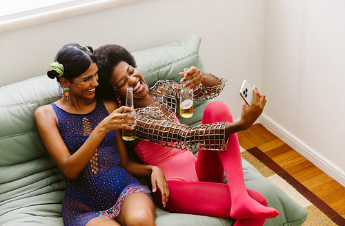 Friends celebrate at home with drinks on couch