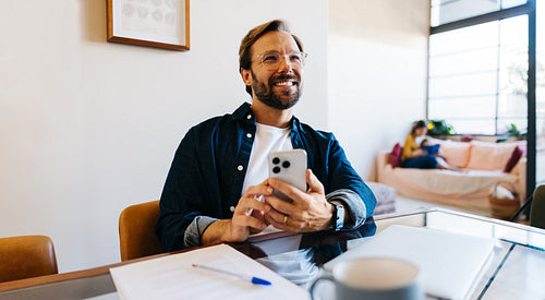 Man smiling at phone in modern cafe