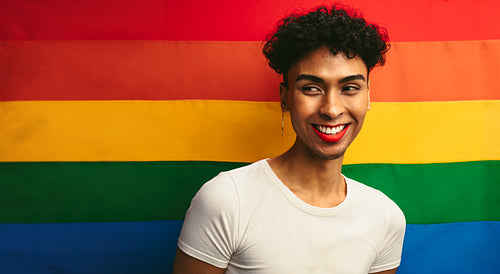 Gay man smiling against pride flag