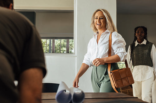 Two professional women entering an office meeting space with enthusiasm and confidence