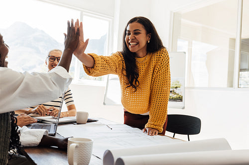 Happy colleagues working together and high-fiving during a creative team meeting