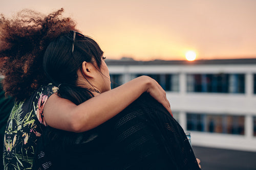 Women relaxing on rooftop and looking at sunset