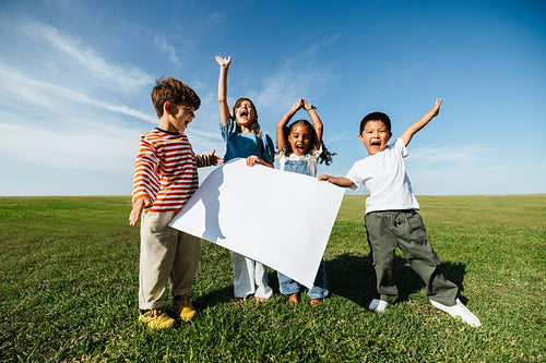Kids celebrate together holding a blank poster outdoors