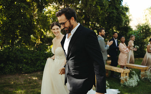 Bride and groom walking away during outdoor wedding celebration with friends