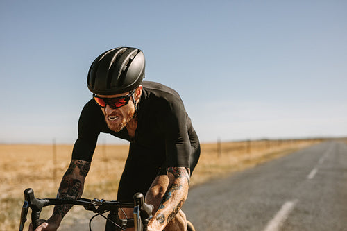 Athlete riding bike along empty road
