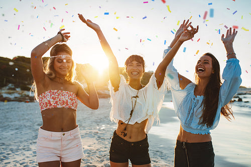 Happy friends partying on the beach with confetti