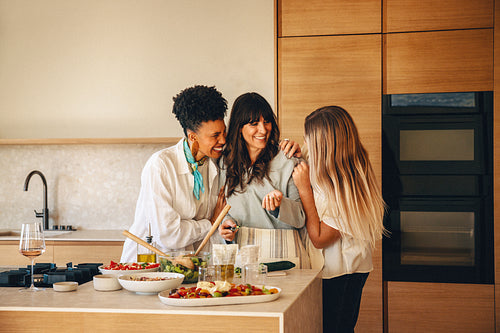 Happy group of female friends cooking together in a modern kitchen