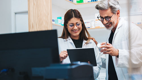 Mature pharmacists using a tablet together in a drug store