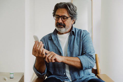 Senior man checks glucose levels at home